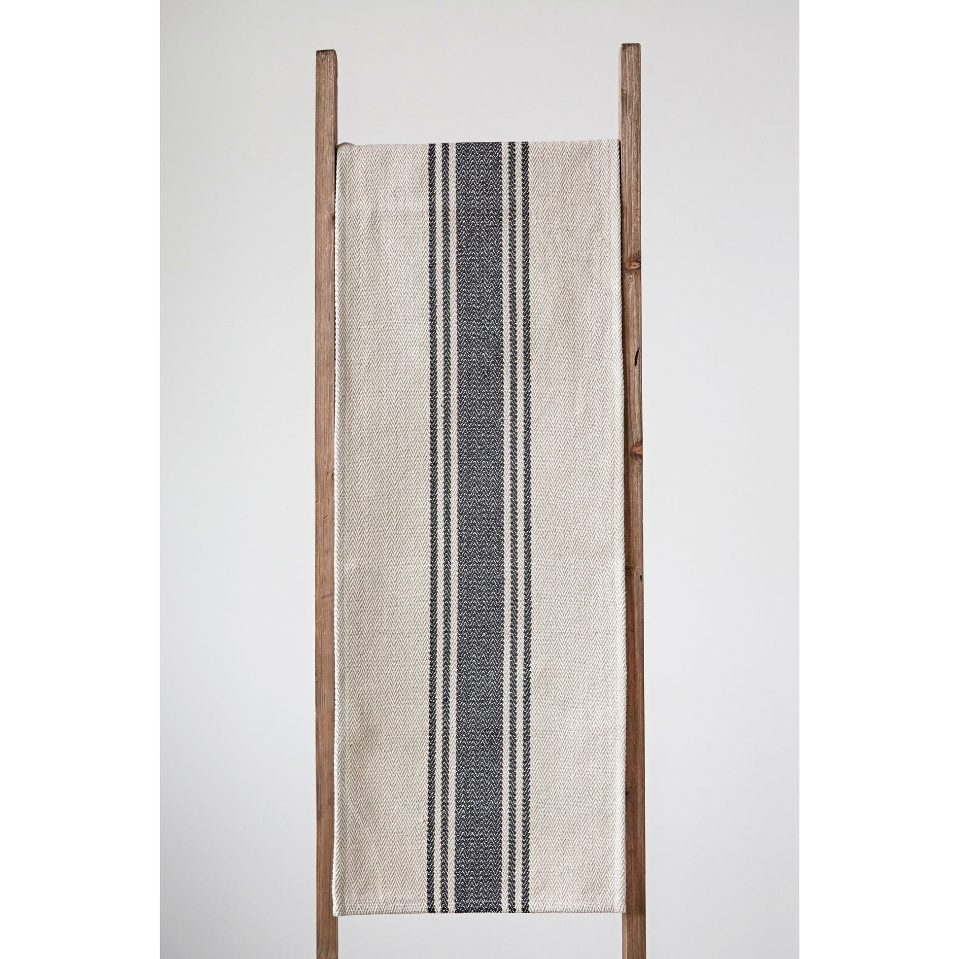 Woven cotton cream and black striped table runner draped over ladder