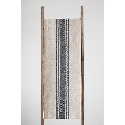 Woven cotton cream and black striped table runner draped over ladder